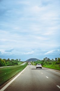 Route nationale en Côte d’Ivoire, avec voiture et colline en fond