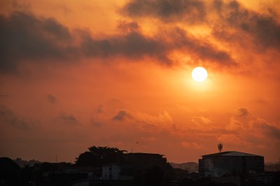 Soleil incandescent sur Abidjan – Ciel flamboyant et contraste urbain