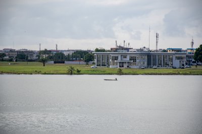 Vue paisible de la lagune d'Abidjan avec la RTI et une pirogue en silhouette