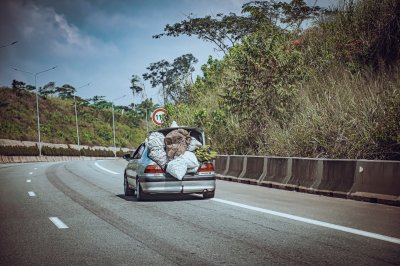 Berline surchargée roulant sur l'autoroute avec le coffre ouvert