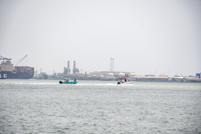 Motorboats filant à vive allure sur le Abidjan lagune avec le industrial zone à le background