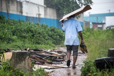 Homme se protégeant himself depuis le pluie avec un cardboard box et tenant his shoes à his hands
