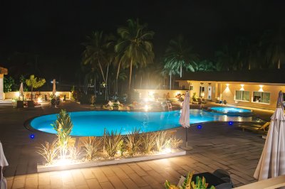 Illuminé piscine à nuit avec tropical palmiers et un moderne hôtel