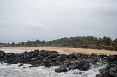 Africain plage avec palmiers et straw paillotes – vagues et rochers par le sea