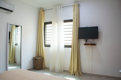 Lumineux chambre avec wall-mounted TV, climatisation, et full-length miroir