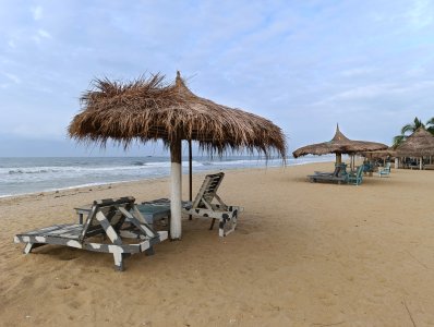 Relaxing view de Fresco plage, Côte d'Ivoire, avec its wooden deckchairs et traditionnel en chaume paillotes face à le Atlantic océan.