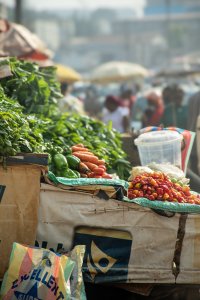 Vertical photograph de un marché étal à Cameroun, displaying fresh légumes piments, carottes, vert feuilles et red piments.