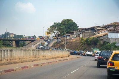 Un typical urban scene à Yaoundé, Cameroun. Yellow taxis et private cars weave along un animé road, entre circulation jams, local bâtiments, et greenery.