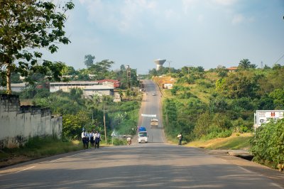 Main road de Mbalmayo, Cameroun. Students walk along le road lined avec luxuriant vegetation et rural dwellings.