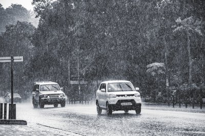 Artistic photograph capturing un scene de intense pluie à Abidjan, Côte d'Ivoire. Two cars are roulant through un heavy downpour.