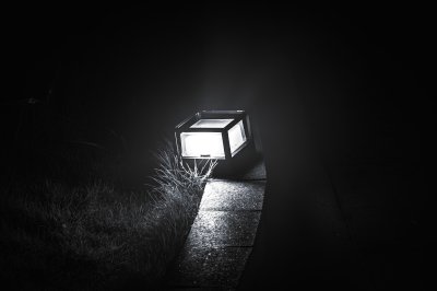 Artistic black et white photograph de un lampe placed sur le floor, diffusing un lumineux light à le heart de le darkness