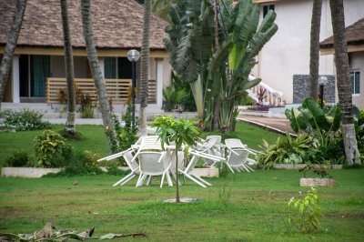 Un calm, verdant tropical jardin within un africain coastal hôtel. Stacked white chairs