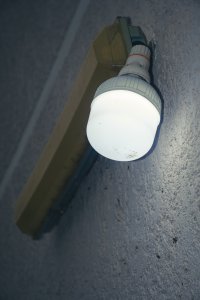 Un éclairé wall bulb is mounted sur un textured wall. le white light creates un calm et functional atmosphere, capturing le aesthetics de everyday life et le beauty de small urban details.