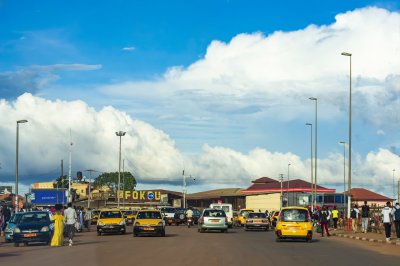 Urban photograph de vie quotidienne à Yaoundé, Cameroun. Yellow taxis, pedestrians, et un striking ciel bleu.