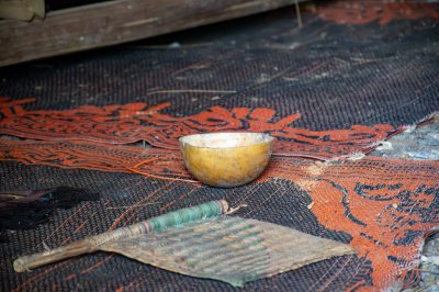Un calebasse et un fan placed sur un rug avec africain patterns, symbolizing camerounais cultural heritage et traditionnel craftsmanship.