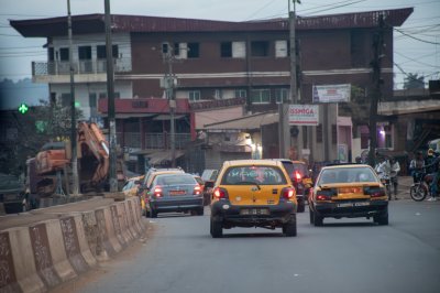 Un popular intersection à Douala avec yellow taxis, shops et residents, illustrating le urban vitality de Cameroun