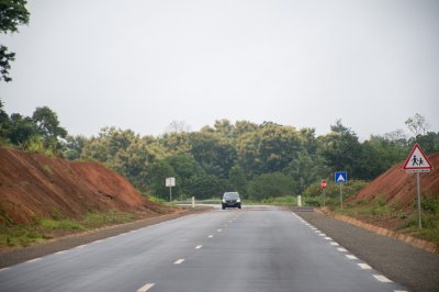 Un paved road bordered par red earth et vert hills, un symbole de le moderne camerounais road network.