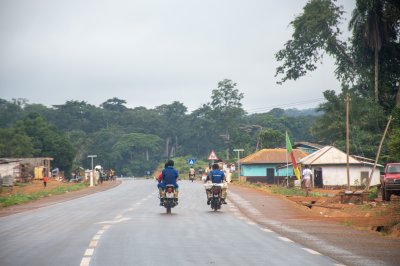 Two motorcyclists traveling sur un national highway lined avec trees et houses