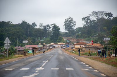 Road passing through un small rural camerounais village avec houses et shops, un typical scene de roadside life.