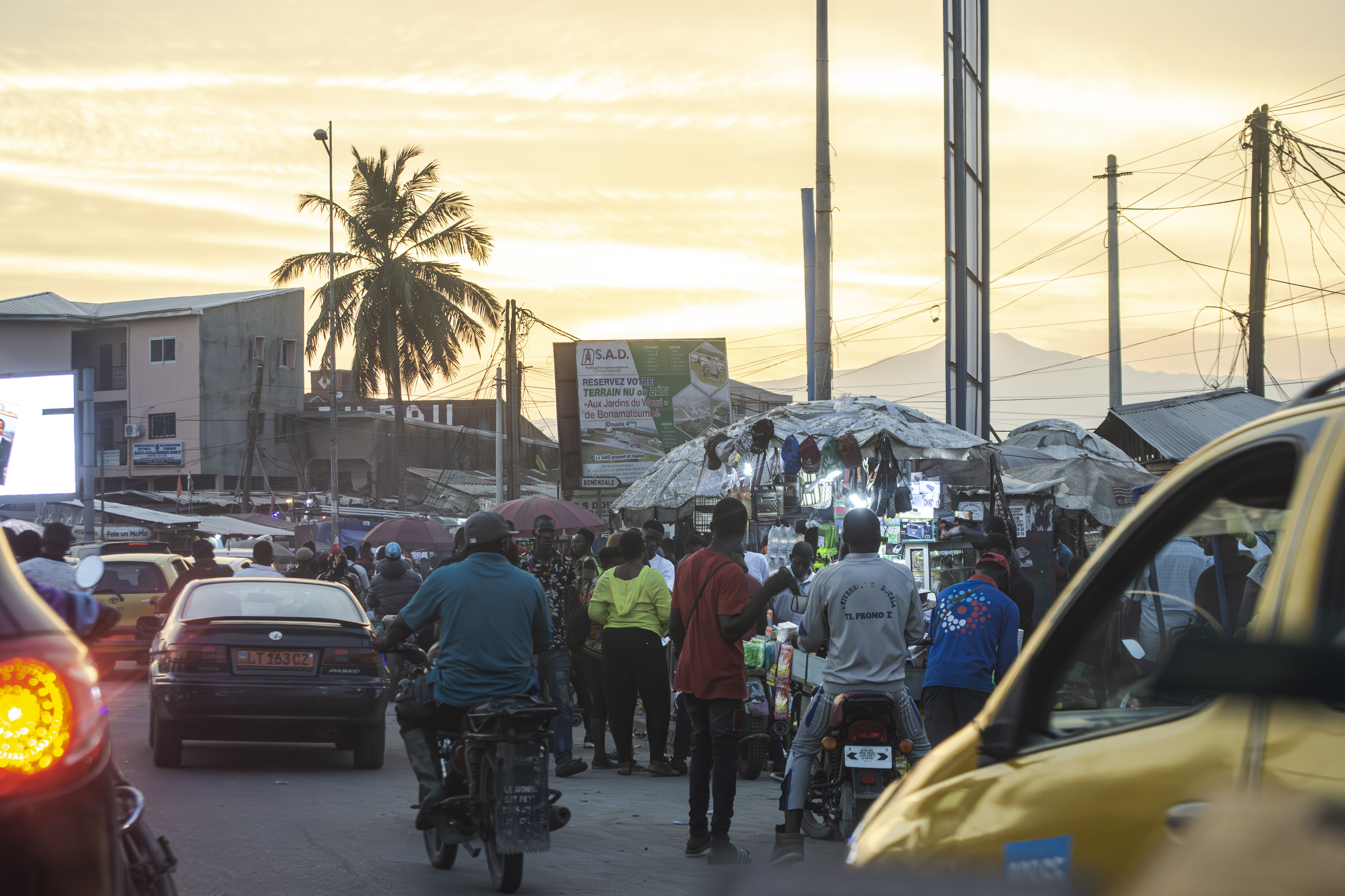 Activité commerciale et Trafic urbain sous un coucher de soleil à Douala