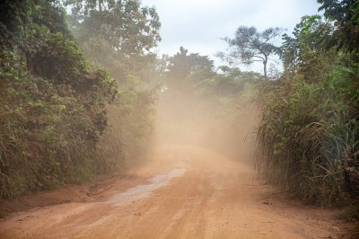 Poussière soulevée par le passage de vehicles sur un route non bitumée au milieu de le forêt