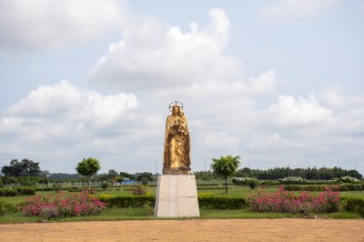 Statue peinte en or de le Vierge Marie avec le enfant Jésus à ses bras à le jardins de le Basilique de Notre-Dame de la Paix à Yamoussoukro