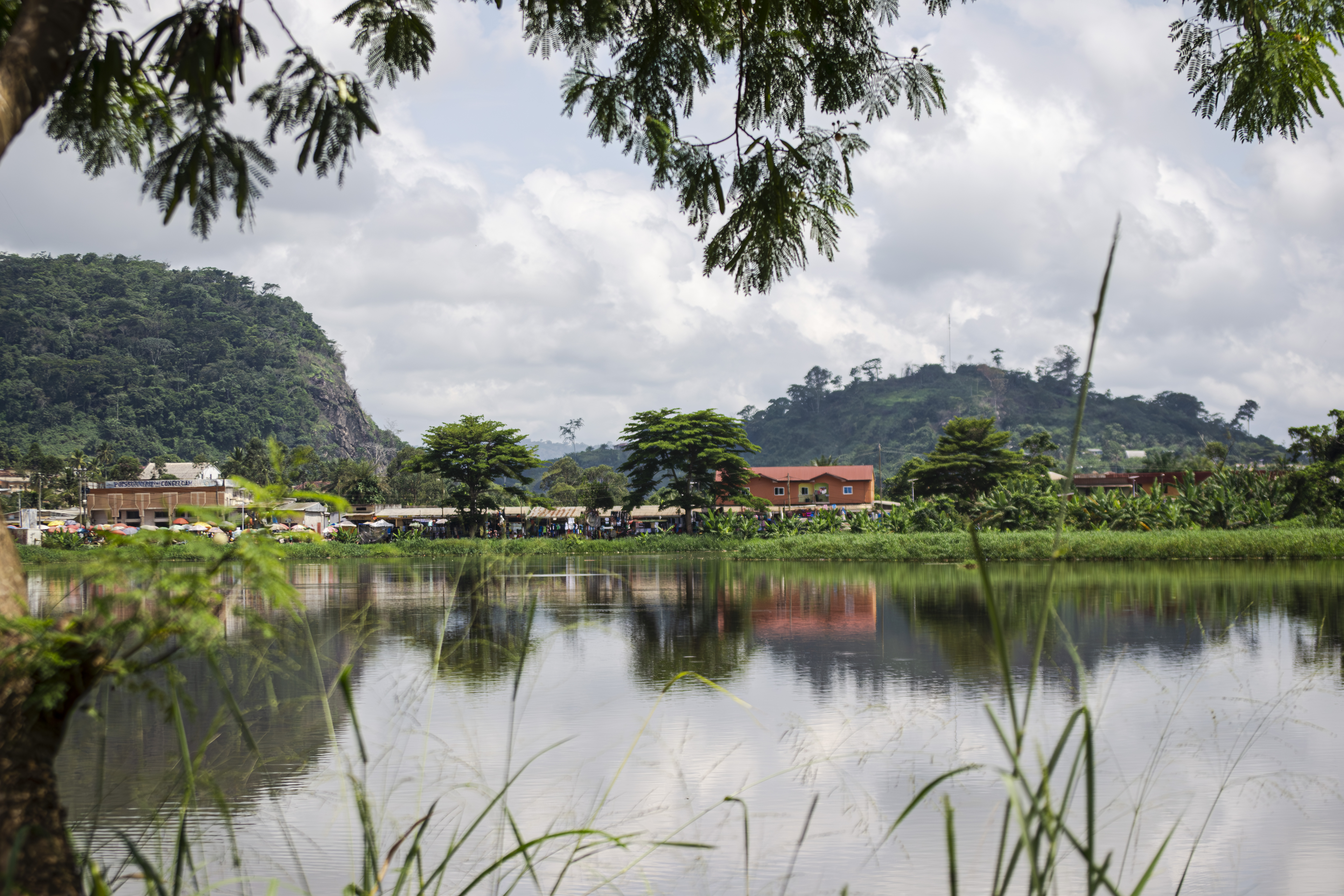 Lac municipal à Ebolowa, Cameroun, avec verdure, bâtiments publics et ciel à le background.