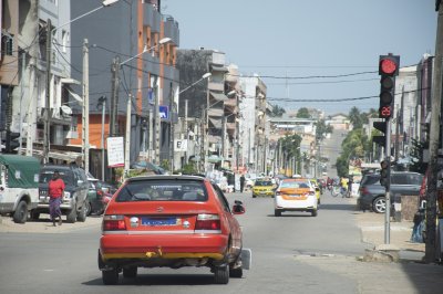 Véhicule rouge arrêté à un feu rouge sur un rue à Abidjan