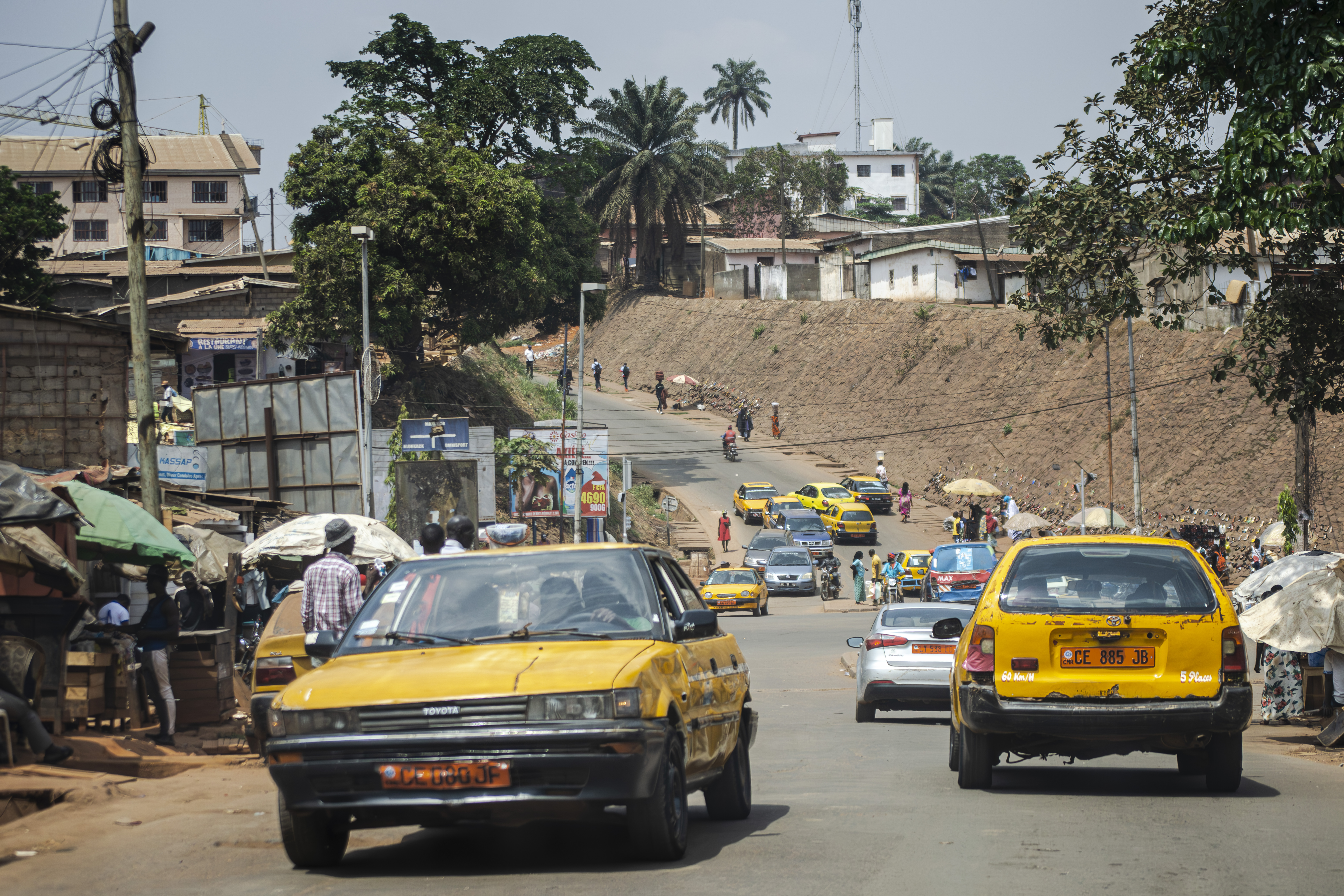 Trafic routier avec gros plan de Taxis jaunes à Carrefour elig edzoa à Yaounde, Cameroun