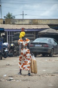Vendeuse de pain sardine, avec un tas de boîtes de sardines sur sa tête et un sac plastique full de bread dans sa main à le streets de Yamoussoukro