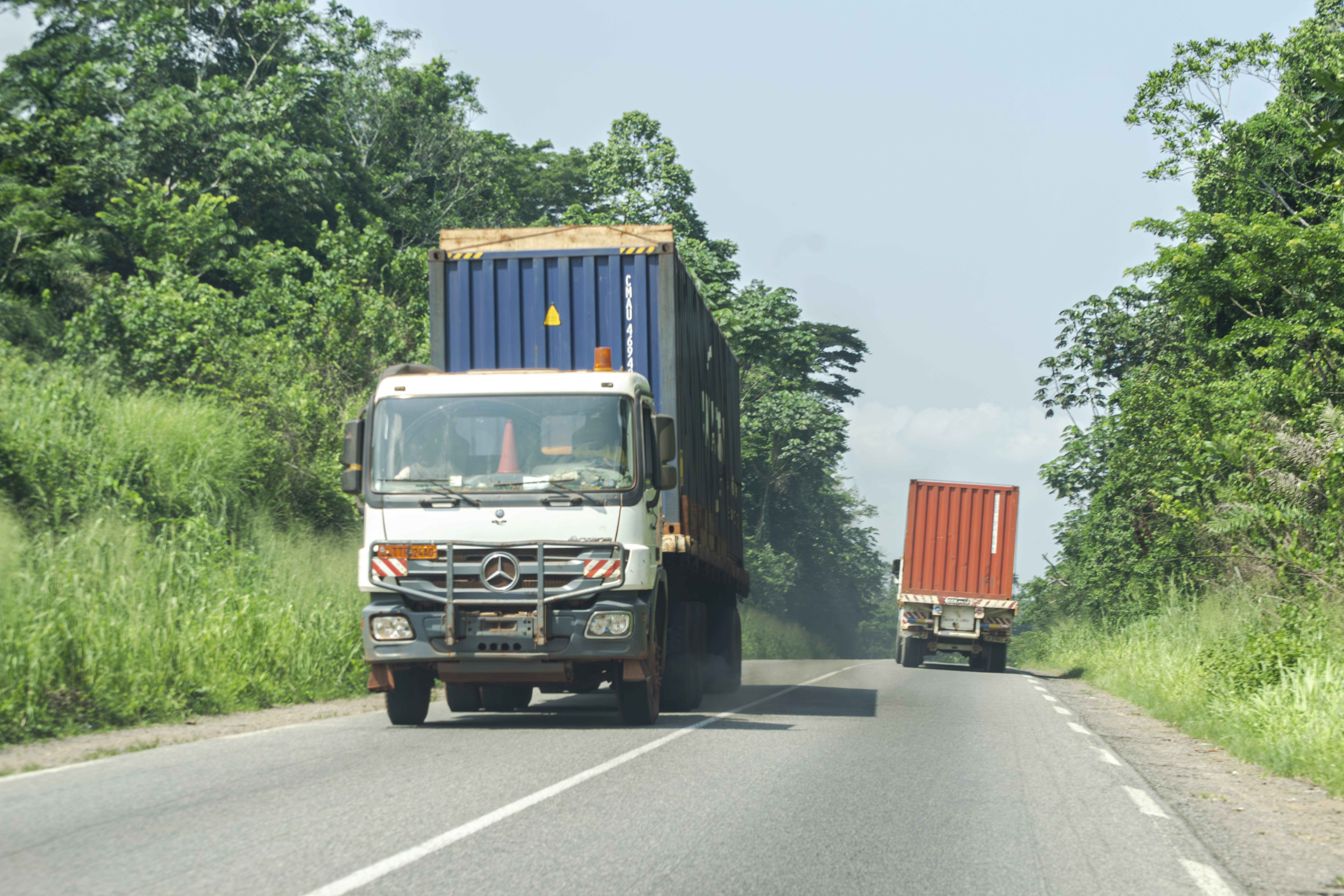 Two poids lourds overtaking each other à opposite directions sur le yaounde - douala route nationale à Cameroun.