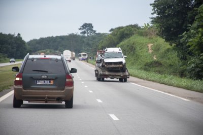 Trafic routier avec damaged voiture transportée par un remorque sur le autoroute à Côte d'Ivoire