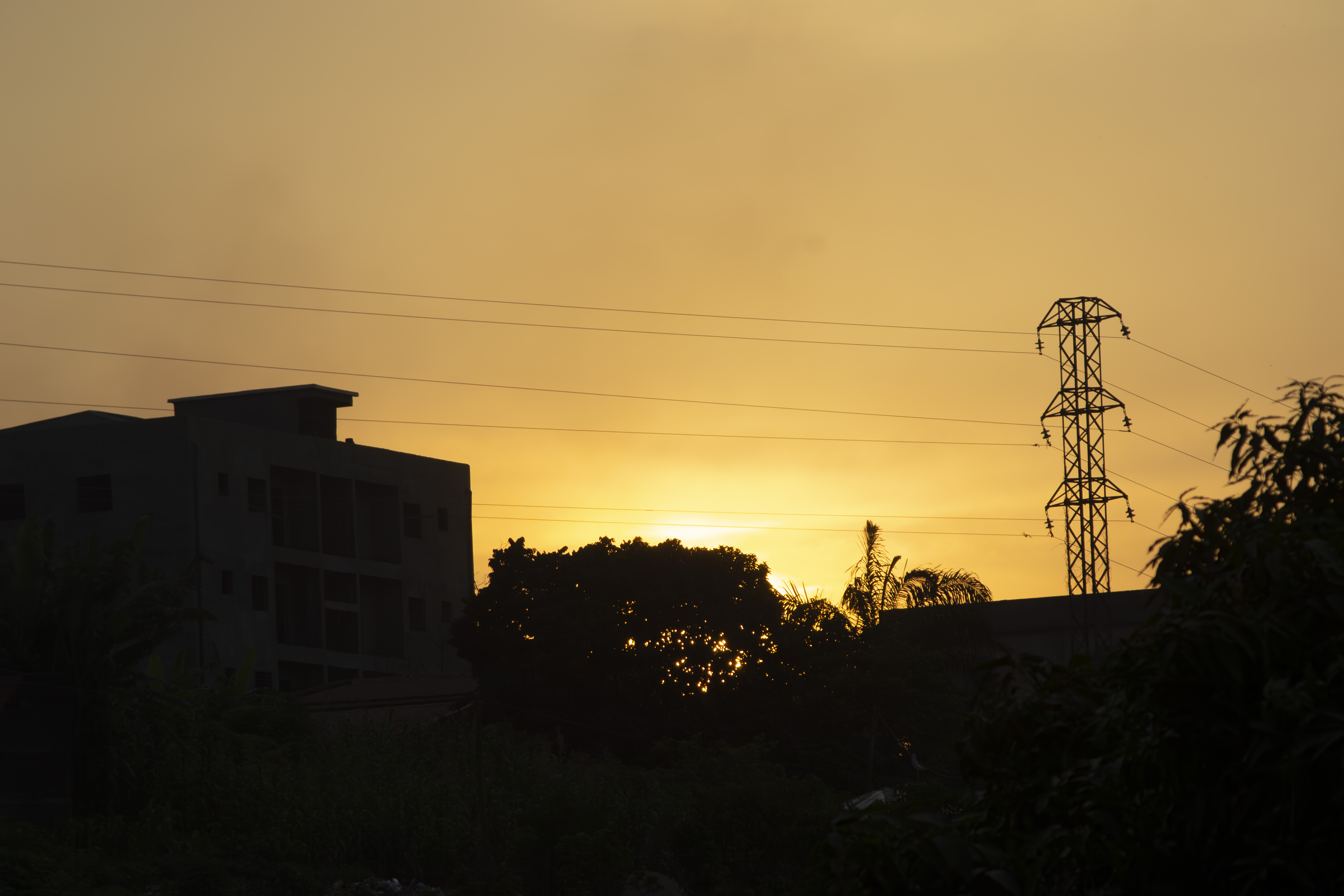 Coucher de soleil avec silhouettes de poteaux électriques, bâtiments et trees à Yaounde 01