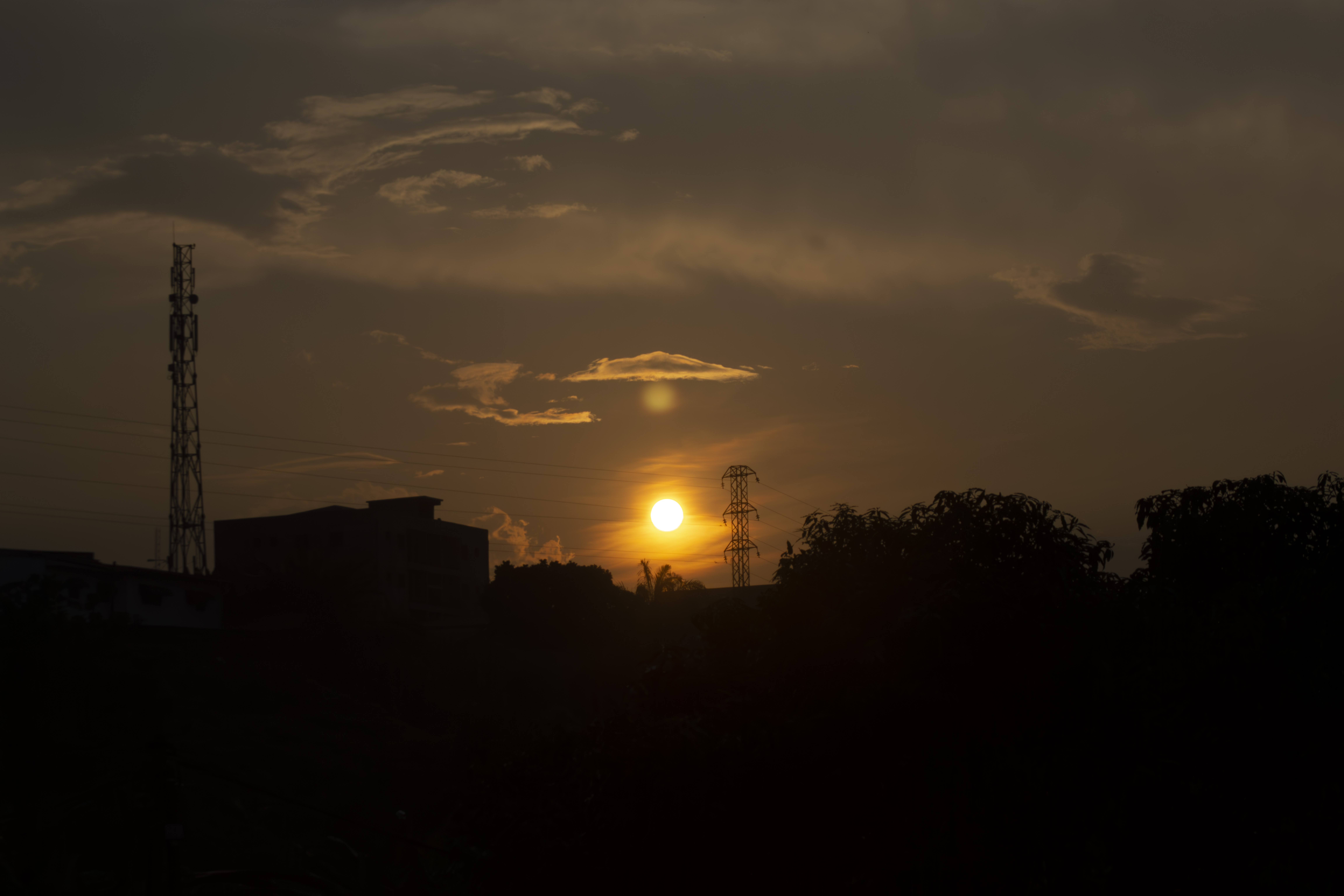 Coucher de soleil avec silhouettes de poteaux électriques, bâtiments et trees à Yaounde, Cameroun.
