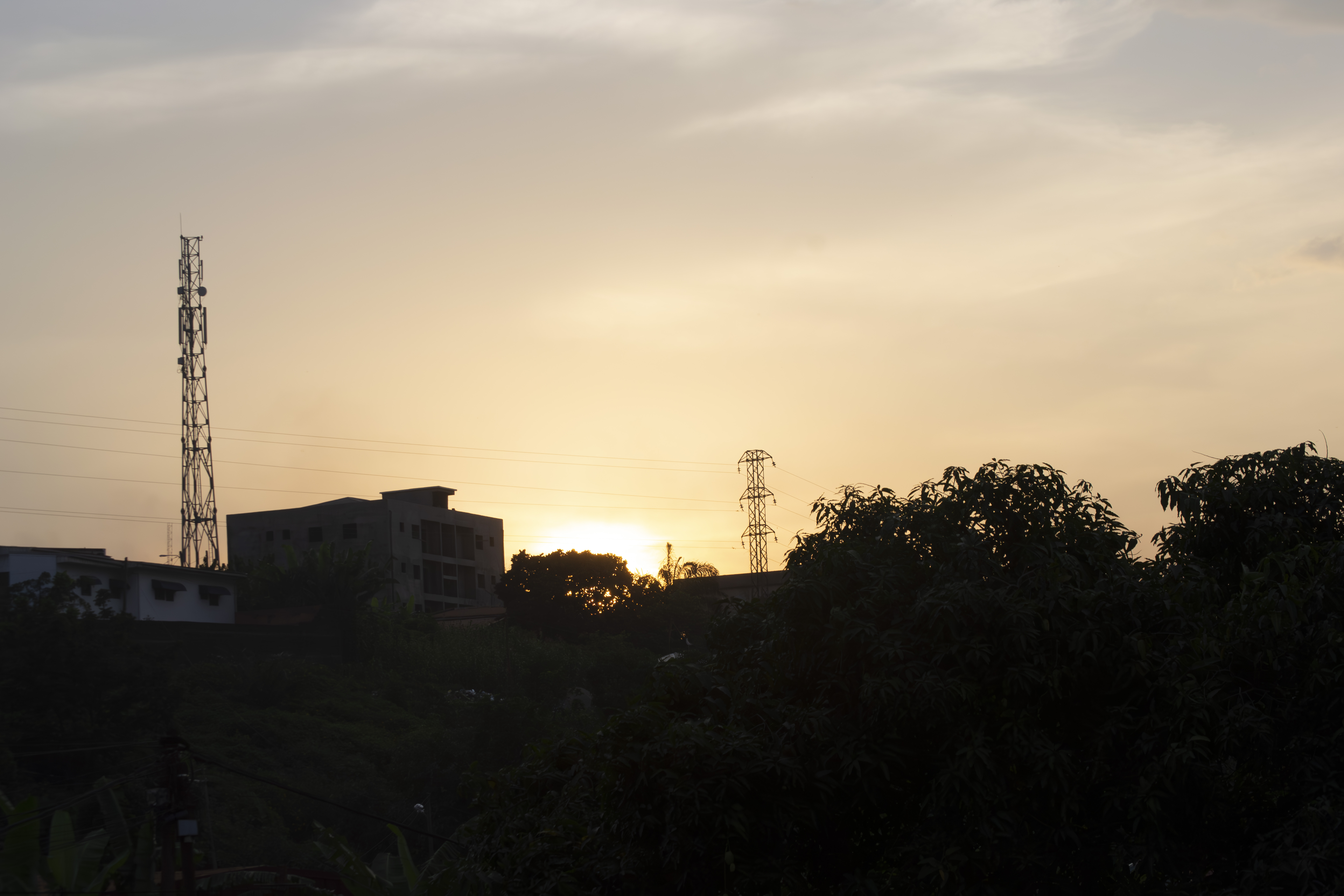 Coucher de soleil avec silhouettes de poteaux électriques, bâtiments et trees à Yaounde