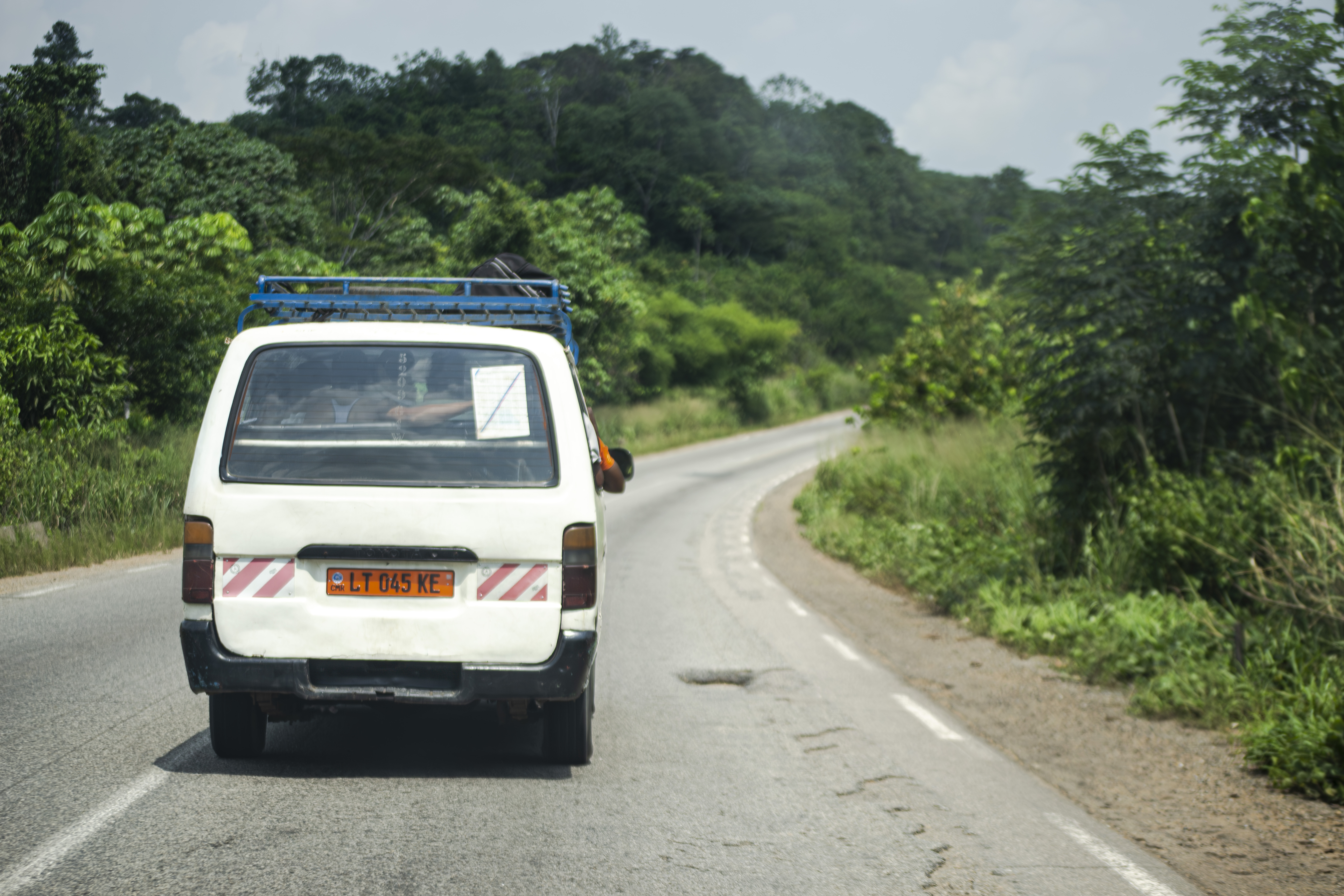 Minibus blanc roulant sur un route déserte à Cameroun